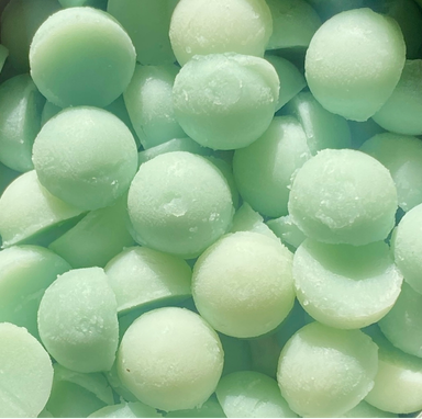 A close-up pile of pale mint green wax melts with a frosted texture.